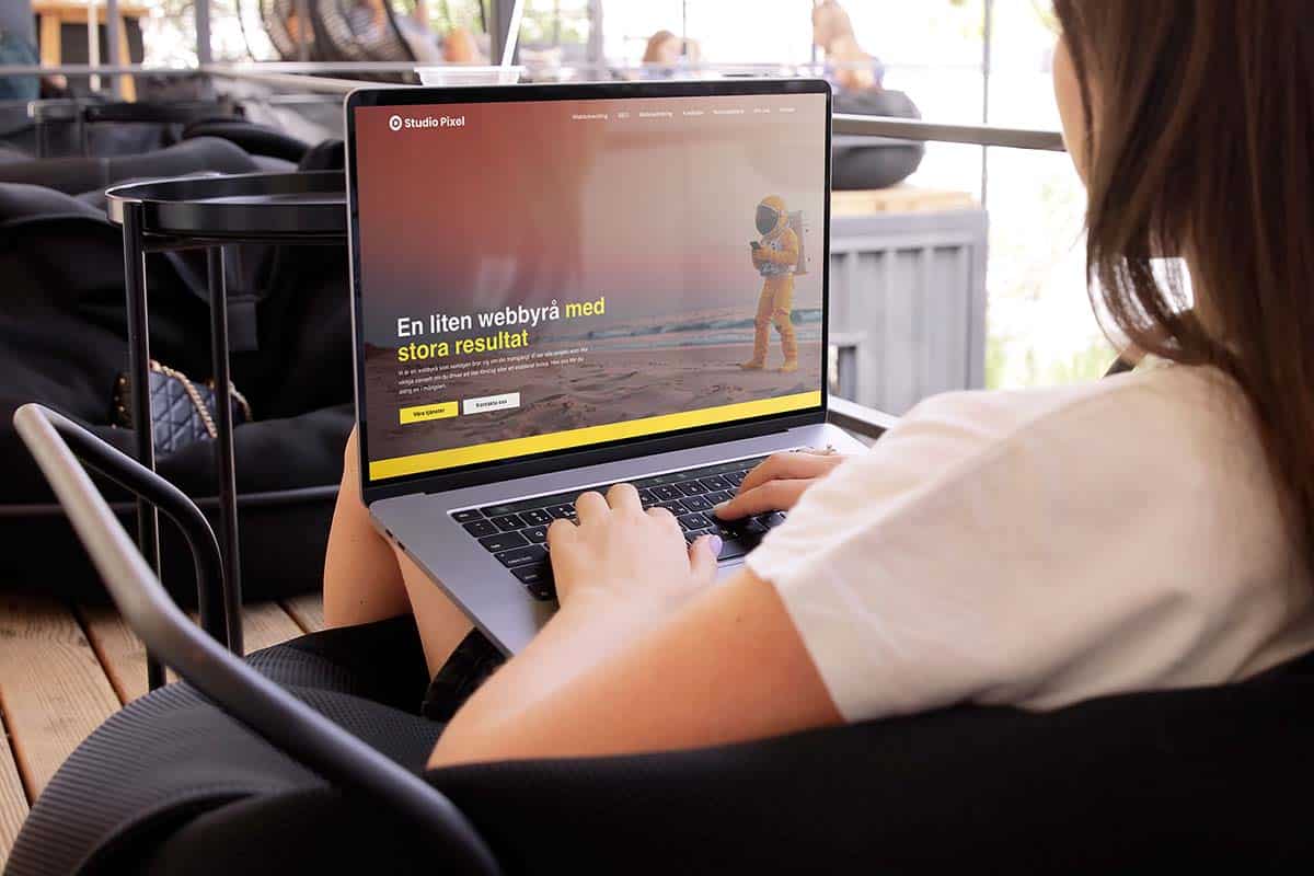 Person sitter i en fåtölj och surfar på Studio Pixels hemsida på en laptop.