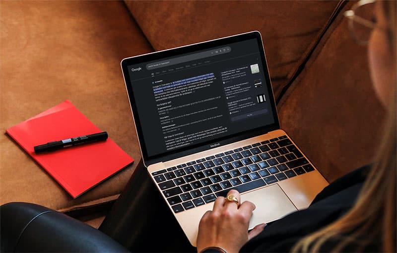 Person som sitter i soffa och använder en laptop. Google AI översikt på skärmen.